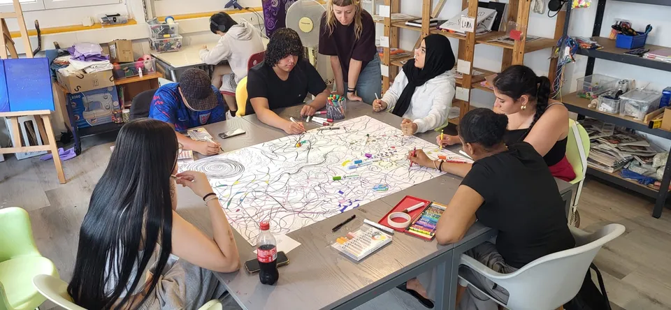 Atelier artistique : un groupe de jeunes dessine autour d’une grande table